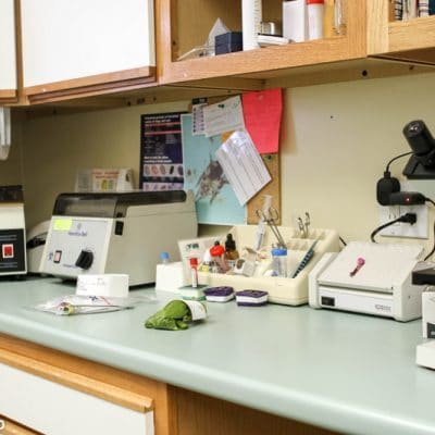 counter of back of office. on counter are several medical devices and supplies such as a microscope and test tubes